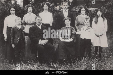 Vintage fotografia di un grande gruppo di famiglia in posa nel loro giardino. Foto Stock