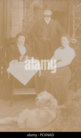 Vintage fotografia di un Edwardian famiglia avente il tè del pomeriggio. Il Golden Retriever presente Foto Stock