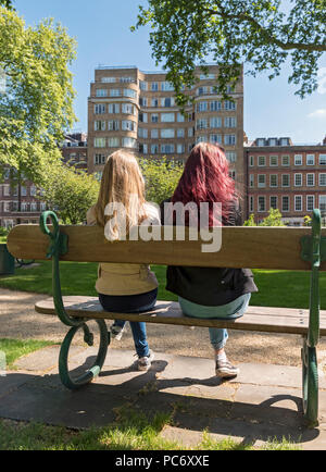 Due ragazze a sedersi su un banco di lavoro al di fuori del Tribunale di Florin edificio aka Whitehaven Mansions residence di Hercule Poirot, Charterhouse Square, London, England, Regno Unito Foto Stock