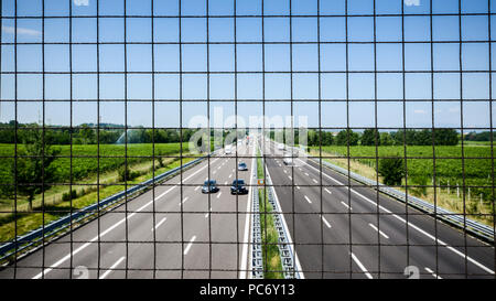 Immagine della catena collegamento recinto sul ponte sul pass. Recinzione di catena sul ponte sopra l'autostrada. Abstract immagine industriale della catena collegamento recinto e auto sulla strada. Foto Stock