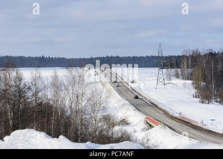 In autostrada in inverno tra i campi. Nevai Foto Stock