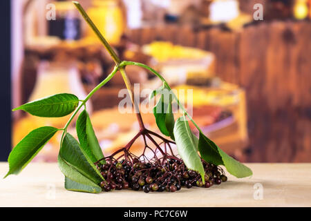 Sacco di intere fresche europeo di sambuco nero un ramo con legno rustico cucina in background Foto Stock