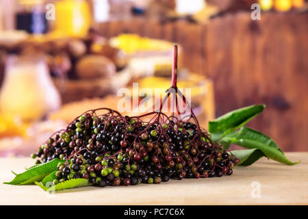 Sacco di intere fresche europeo di sambuco nero con legno rustico cucina in background Foto Stock