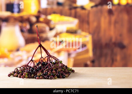 Sacco di intere fresche europeo di sambuco nero un ramo senza foglie con legno rustico cucina in background Foto Stock