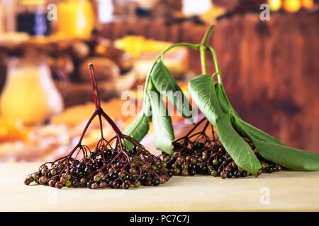 Sacco di intere fresche europeo di sambuco nero due rami con legno rustico cucina in background Foto Stock