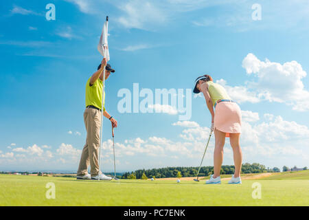 Golf femminile il giocatore pronto per colpire la palla sotto la guida di un maestro di golf Foto Stock