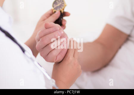 Infermiera femmina controllo pazienti impulso. Offerta mano del medico donna tenendo premuto con due dita per pazienti di polso per il controllo di impulso. Utilizzo di guardare per il timer. Foto Stock