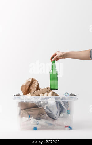 Ritagliato colpo di donna mettendo una bottiglia di vetro nel contenitore con bottiglie di plastica, concetto di riciclo Foto Stock