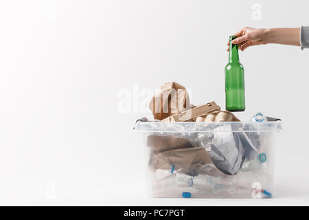 Ritagliato colpo di donna mettendo una bottiglia di vetro nel contenitore con bottiglie di plastica, concetto di riciclo Foto Stock