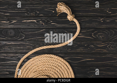 Vista parziale di marrone annodata corda nautica disposti in cerchio sulla superficie di legno Foto Stock