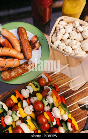 Salsicce calde e verdure con funghi su spiedini grigliata per barbecue all'aperto Foto Stock