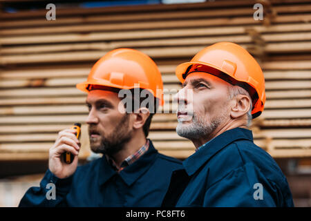 Due costruttori nei caschi lavora con walkie talkie fuori in costruzione Foto Stock