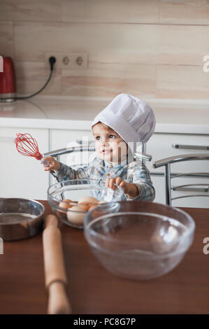 Adorabili poco capretto in chef hat holding frusta in mano pronti per cucinare Foto Stock