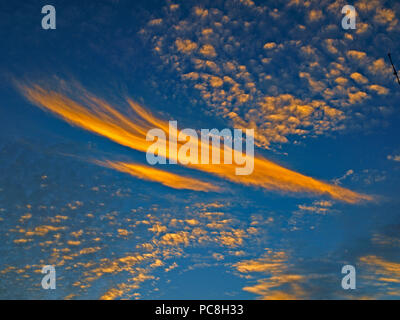 Una spettacolare luminosamente atmosferica di colore arancio e blu cielo nuvoloso cloudscape dotato di un Altocumulus e Cirrus cloud formazione in una metà del cielo blu Foto Stock