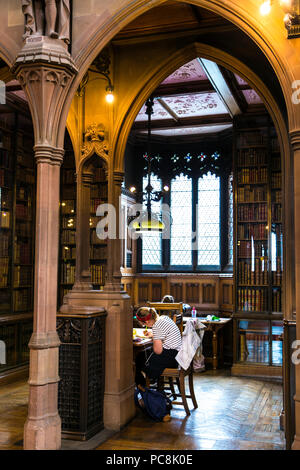 Donna allo studio, alla ricerca di un vecchio biblioteca sala lettura, John Rylands Library e Manchester, Regno Unito Foto Stock