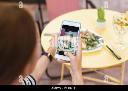 Blogger moderno. Moderno famoso blogger rendendo la foto del suo insalata estiva seduti nel ristorante Foto Stock