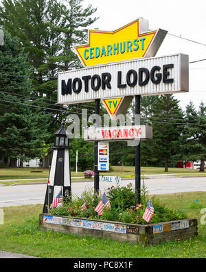 Un Cedarhurst Motor Lodge segno con giardino fiorito, faro e bandierine americane in speculatore, NY USA Foto Stock