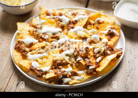 Peperoncino carni bovine nachos con panna acida e formaggio grattugiato Foto Stock