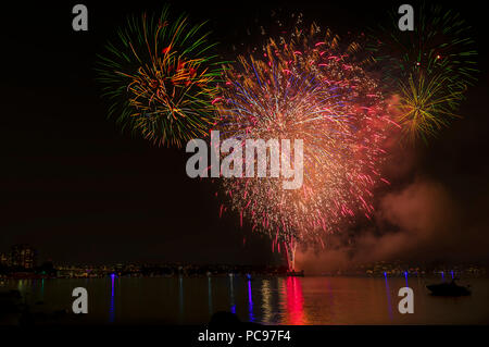 Multi Colore luci di fuochi d'artificio sull'oceano in una grande città, antico ponte e moderni edifici sullo sfondo, incandescente e di riflessione del paglierino Foto Stock