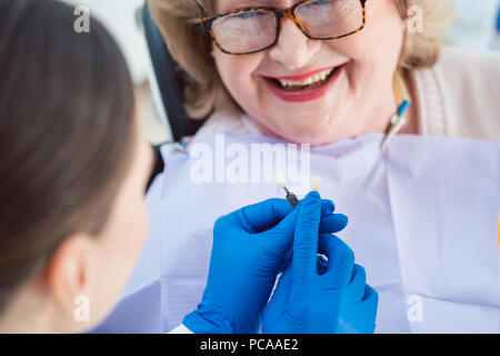 Dentista donna eseguendo sbiancamento dentale al paziente senior Foto Stock