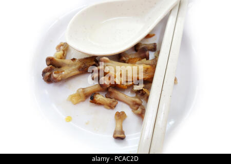 Le ossa del pollo su una piastra bianca con baguette e cucchiaio Foto Stock