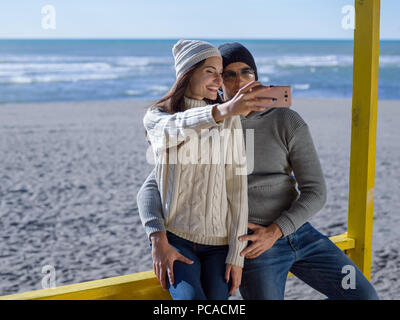 Molto felice coppia In amore tenendo Selfie sulla spiaggia in autmun giorno Foto Stock