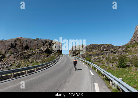 Femmina ciclista su strada sulla strada di Henningsvaer, Isole Lofoten in Norvegia. Foto Stock