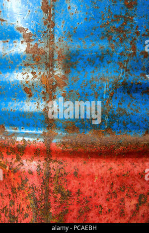 La parete di fusti di metallo verniciato di rosso e di vernice blu con tracce di ruggine Foto Stock