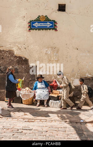 Donna locale in abbigliamento tradizionale vendita di varie spezie e spuntini secchi, una prelibatezza locale. Vintage mercato Sud Americano. Cusco, Perù Foto Stock
