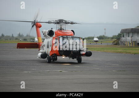 Una guardia costiera equipaggio a bordo di un MH-60 Jayhawk elicottero atterra al settore Columbia River in Warrenton, Ore., per erogare un malato pescatore in attesa di servizio medico di emergenza, 31 luglio 2018. L'equipaggio medicalmente evacuato il pescatore malato off la pesca commerciale nave Zena D 100 miglia fuori della Città del Pacifico, Ore., costa. Stati Uniti Coast Guard foto di Sottufficiali di prima classe Levi leggere. Foto Stock