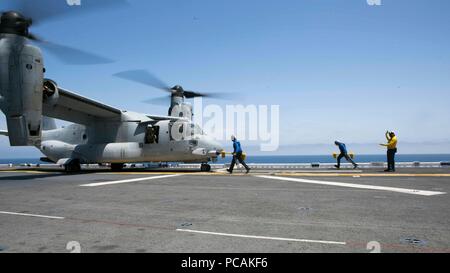 Oceano Pacifico - U. S. marinai della marina con la Essex anfibio gruppo pronto (ARG) Bloccare i pneumatici di un MV-22B Osprey con Marine mezzo squadrone Tiltrotor 166 rinforzato, xiii Marine Expeditionary Unit (MEU), nel corso di una regolare distribuzione programmata dell'Essex ARG e la tredicesima MEU, luglio 11, 2018. L'Essex ARG/MEU team è un forte e flessibile, reattivo e forza coerente in grado di manovrare la guerra tra tutti i domini; esso è attrezzato e dotato di una soluzione scalabile in grado di rispondere a qualsiasi crisi di assistenza umanitaria e di soccorso in caso di catastrofe per le operazioni di emergenza. (U.S. Marine Corps foto di Cpl. A. J. Van Frede Foto Stock