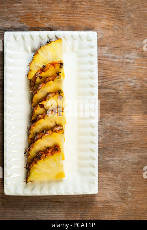 Ananas frutta tagliata a spicchi su piastra di sfondo di legno snack sani Foto Stock