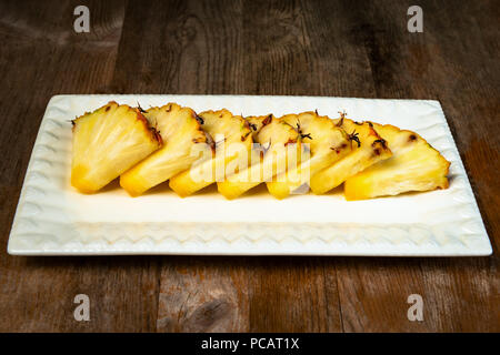 Ananas frutta tagliata a spicchi su piastra di sfondo di legno snack sani Foto Stock