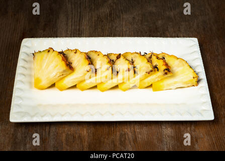 Ananas frutta tagliata a spicchi su piastra di sfondo di legno snack sani Foto Stock