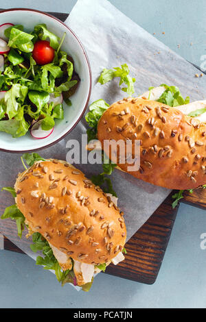 Due sandwich con pollo e rucola su tavola di legno con insalata vista dall'alto. Nutriente e salutare prima colazione Foto Stock