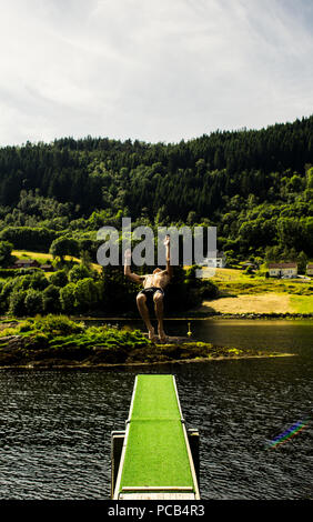 Backflip fuori da un trampolino in un lago circondato da alberi Foto Stock