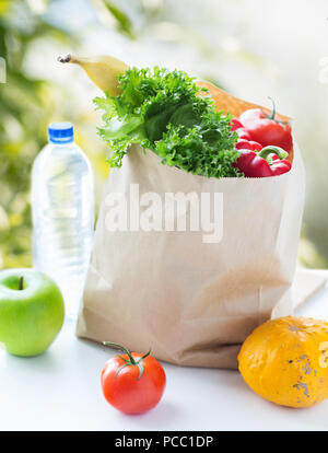 Sacchetto di carta vegetale con cibo e acqua sul tavolo Foto Stock