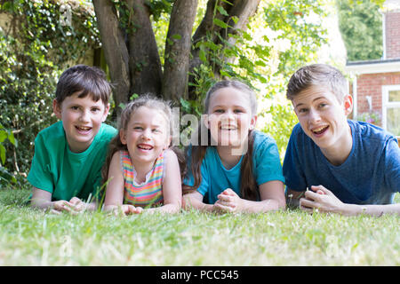 Ritratto di quattro fratelli e sorelle giacente nel giardino di casa Foto Stock