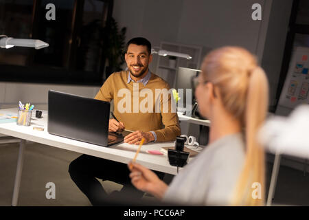 Designer con laptop a parlare con un collega in ufficio Foto Stock