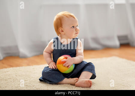 Bella redhead bambina con sfera di giocattolo a casa Foto Stock