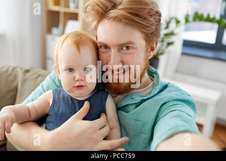 Padre felice con il bambino tenuto selfie a casa Foto Stock