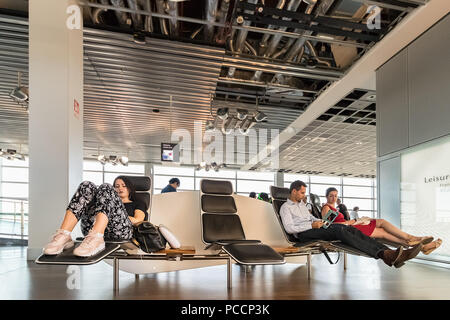 Francoforte, Germania - Luglio 3th, 2018: passeggeri in appoggio in sedili reclinabili nella sala di attesa in aeroporto di Francoforte am Main. Foto Stock