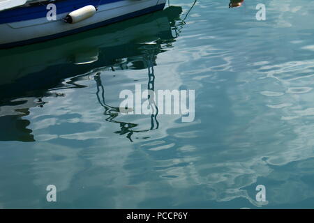 Un riflesso di una barca in acqua di mare sul porto di Limenas Thassos, Grecia Foto Stock