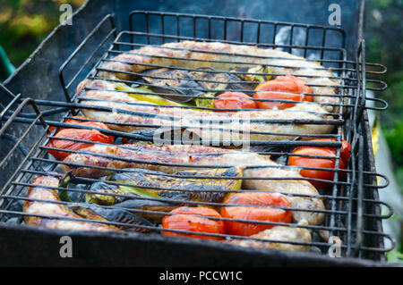 Salsicce di maiale con verdure alla griglia sul fuoco. Cucinare la cena all'aperto. Foto Stock