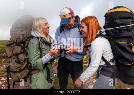 Viaggiare lo stile di vita e il concetto di sopravvivenza vista posteriore. Escursionismo uomo e donna con zaino gode di una escursione e guarda le foto scattate sulla fotocamera in m Foto Stock