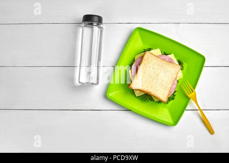 Formaggio e prosciutto sandwich, bottiglia di acqua bianco su un tavolo di legno. Pranzo sano concetto idea. Vista dall'alto. Ancora in vita. Copia spazio. laici piatta Foto Stock