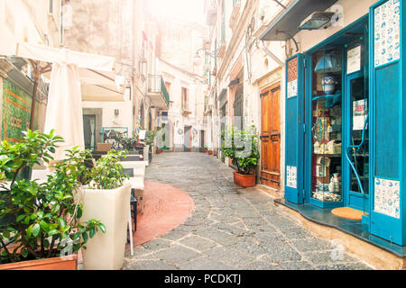 VIETRI-sul-mare, Italia - 3 settembre, 2017: vista del vuoto stretta strada piena di caffetterie e negozi di souvenir di prima mattina con il sole che splende attraverso il Foto Stock