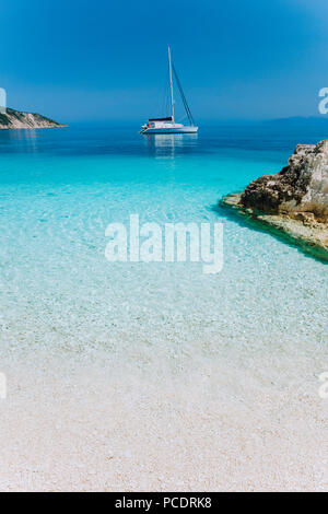 Meraviglioso azzurro laguna blu con catamarano a vela yacht barca ad ancoraggio. Bianco puro e sulla spiaggia di ciottoli, alcune rocce in mare. Foto Stock