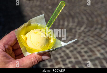 Scoop di gelato al limone in un contenitore di plastica con il cucchiaio. Foto Stock