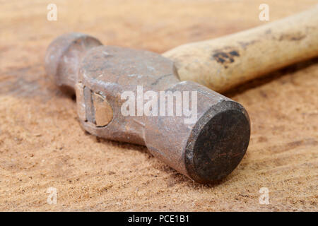 Ripresa macro di un vecchio arrugginito martello per l'inserimento di sfere su una tavola di legno Foto Stock